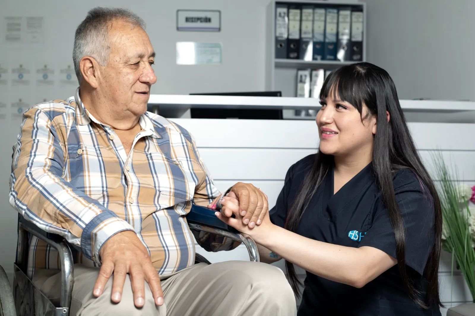 Una enfermera de Health Support toma de las manos a un paciente mayor