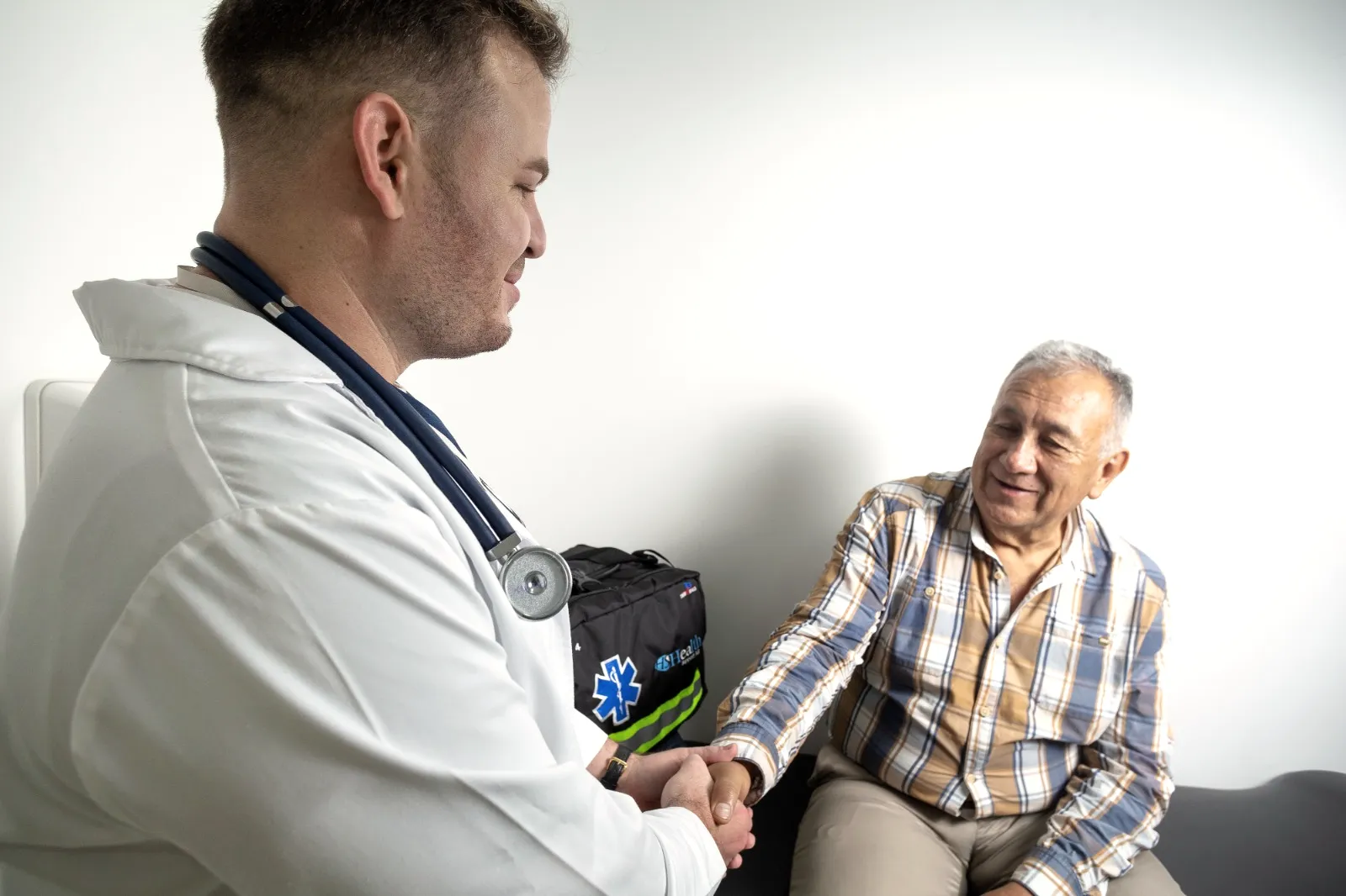 Un médico de Health Support saluda de la mano a un paciente mayor en la sede